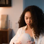 A focused woman with curly hair types on a typewriter in a warmly lit indoor setting, creating content.