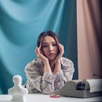 Pensive woman with typewriter in an artistic setting, perfect for creative themes.